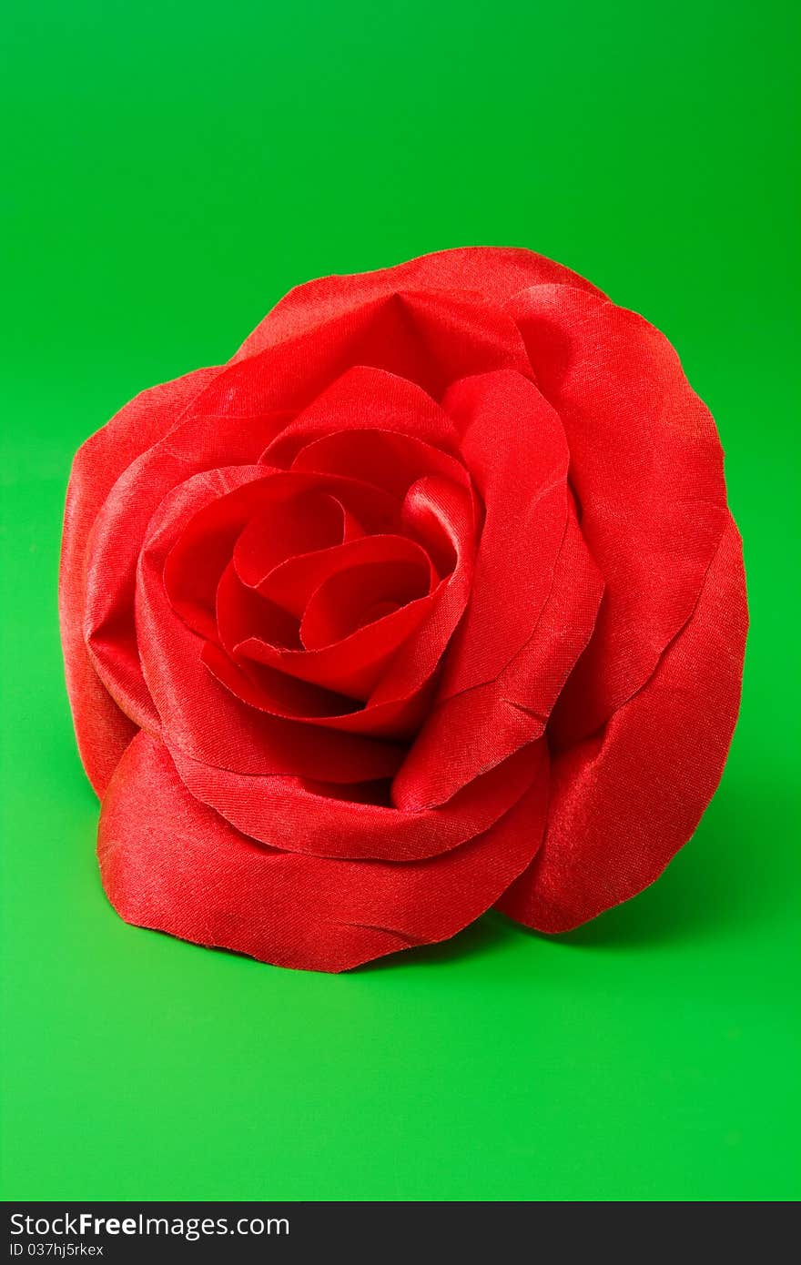 Decorative red silk rose on green