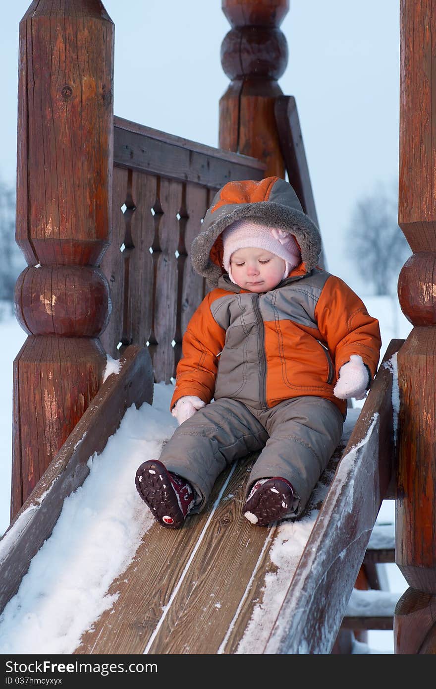 Cute baby prepare to slide down the slides for children in winter