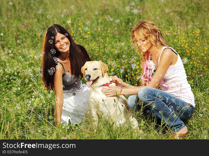 Girlfriends and dog in green grass field