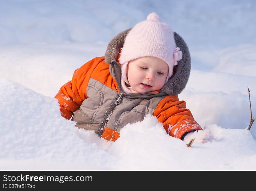 Cute baby sit in snow in forest and dig snow