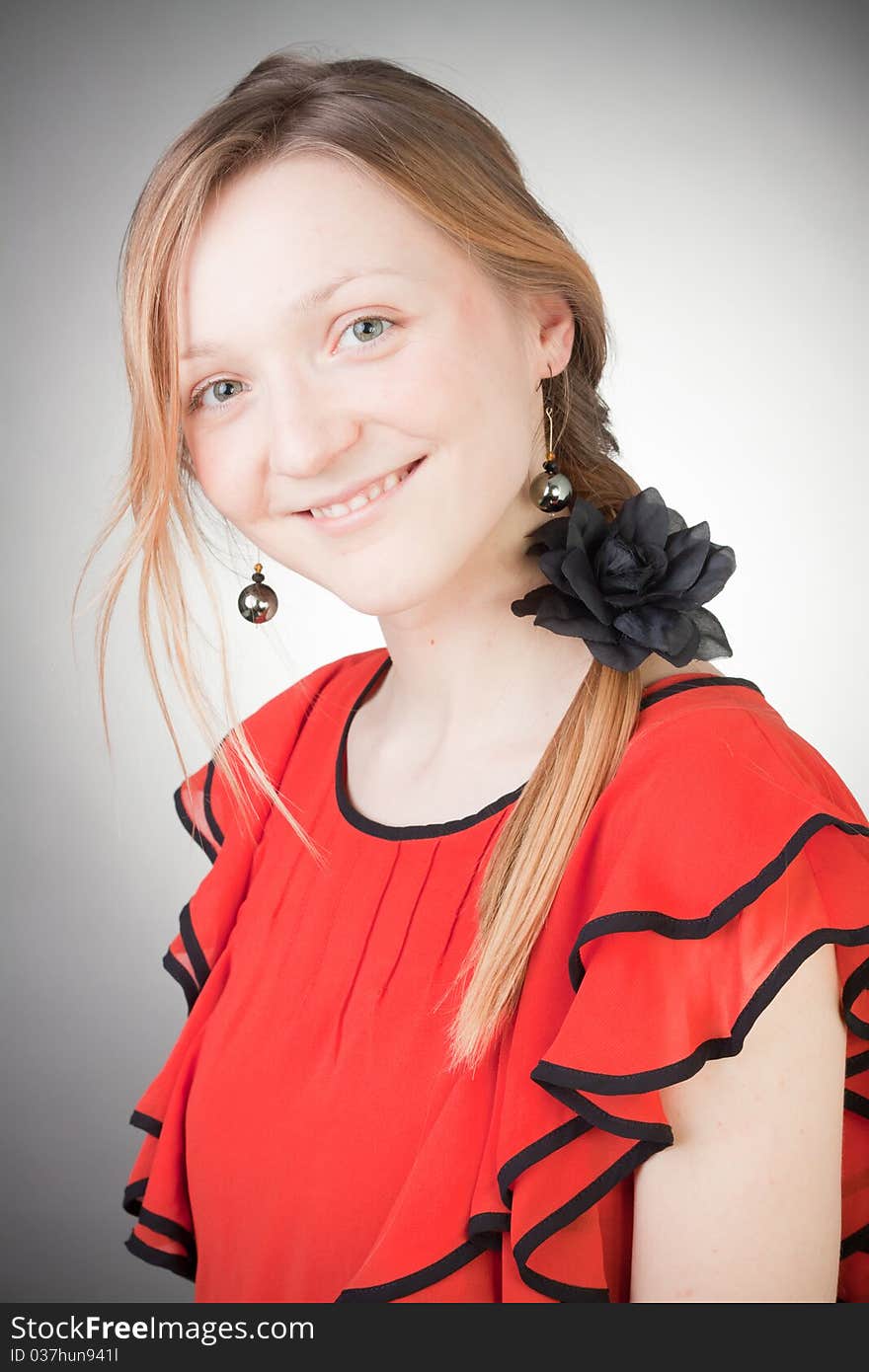 Beautiful blond woman wears red dress, smells black flower, with grey background