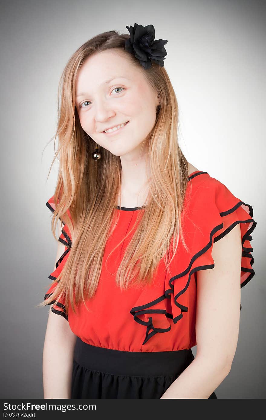 Beautiful blond woman wears red dress, smells black flower, with grey background