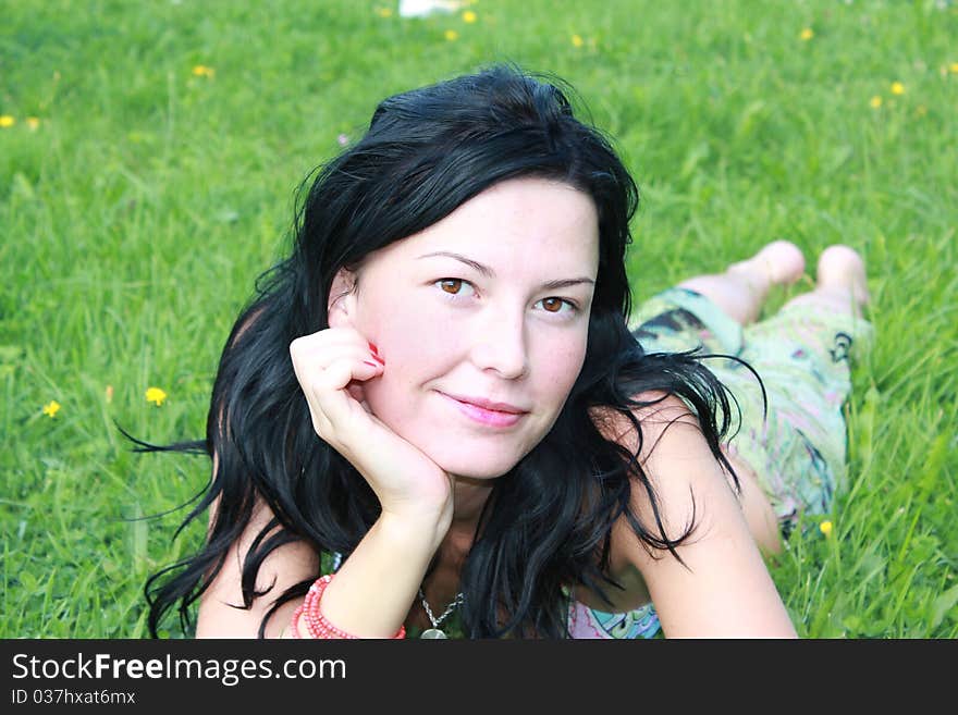 Young beautiful girl lying on green grass