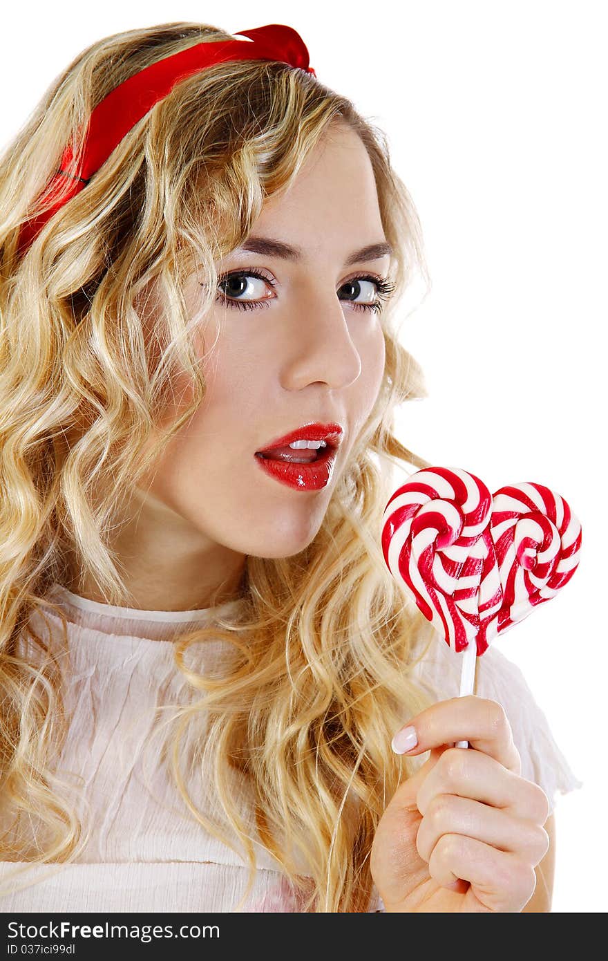 Beautiful young girl with a candy in the shape of a heart. Beautiful young girl with a candy in the shape of a heart