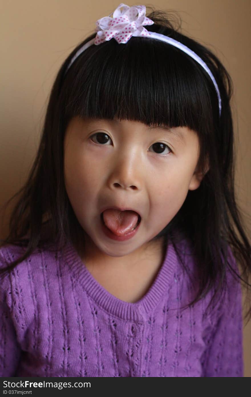 Cute young Asian girl pulling funny face with tongue out, studio background. Cute young Asian girl pulling funny face with tongue out, studio background.