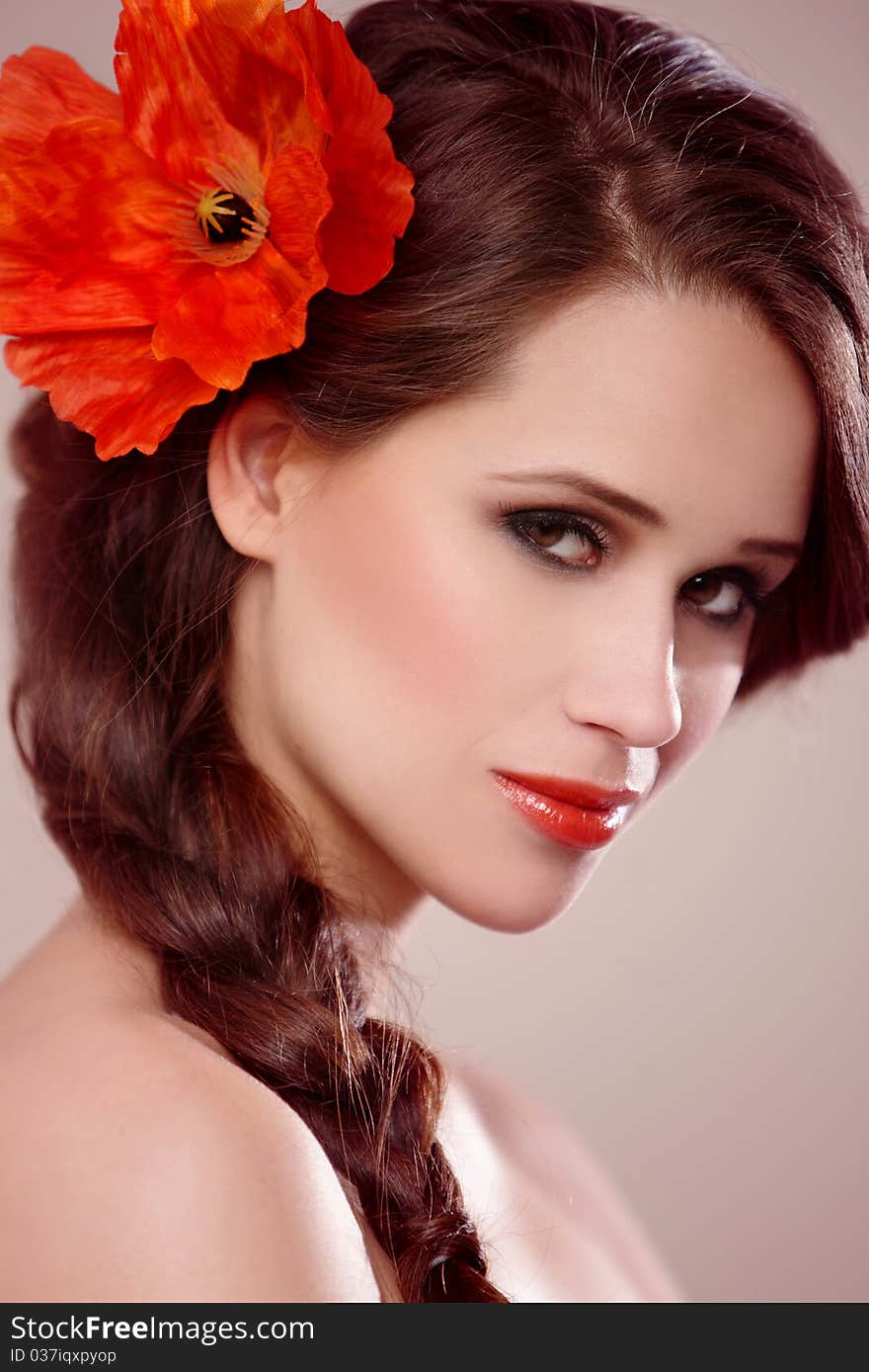 Portrait of a beautiful woman with a braid and flower on natural background