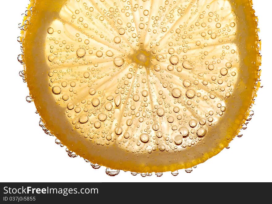 Partially transparent lemon slice floating in effervescent liquid