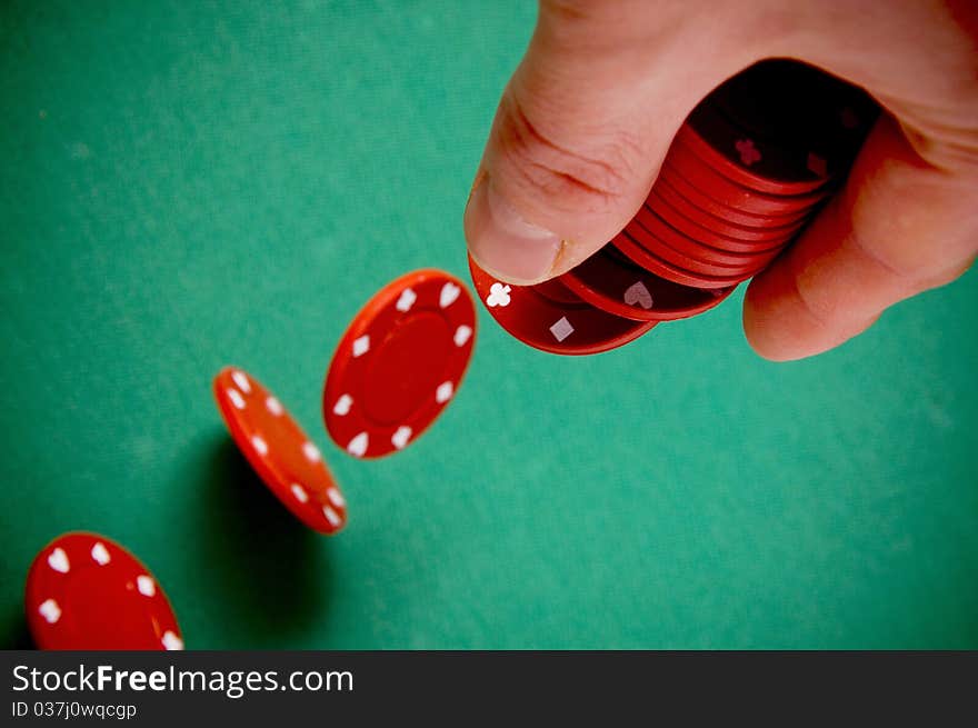 Red gambling chips falling from men hand