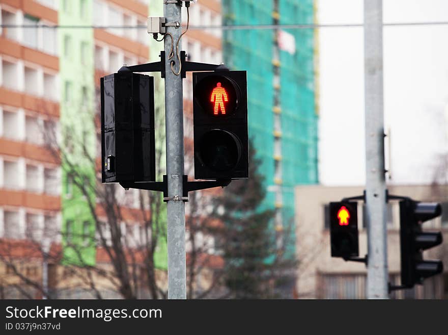 Red pedestrian traffic light with buildings on background