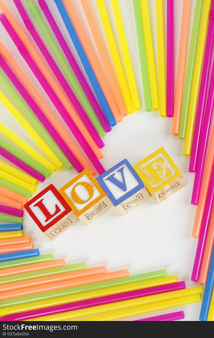 Colorful Straws make a heart shape and childrens bloks spell the word Love. Colorful Straws make a heart shape and childrens bloks spell the word Love.