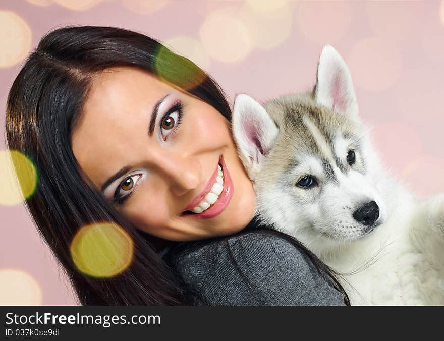 Playing woman with puppy of siberian haski on pink background with confetti. Playing woman with puppy of siberian haski on pink background with confetti