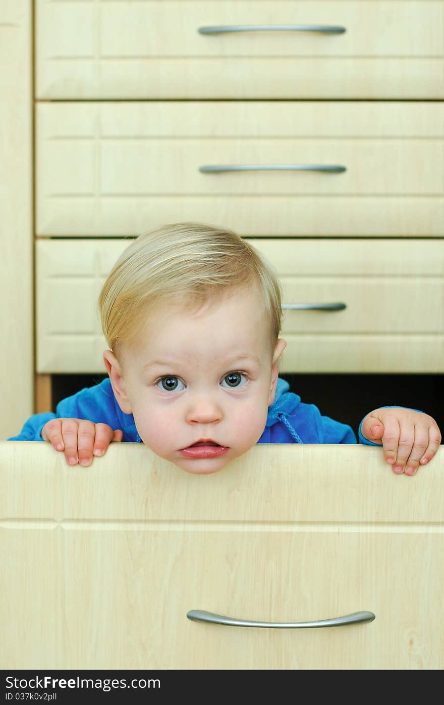 White haired little boy in the kitchen cabinet