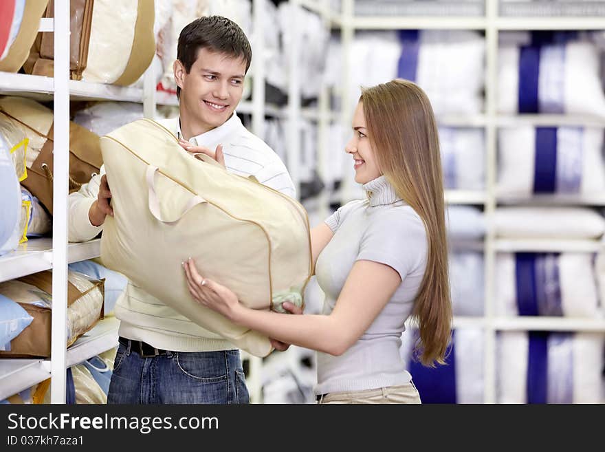 Man gives a girl the pillow in the store. Man gives a girl the pillow in the store