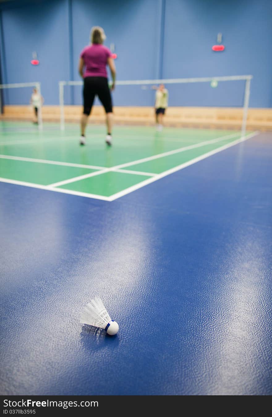 Badminton - badminton courts with players competing; shuttlecocks in the foreground (shallow DOF; color toned image)