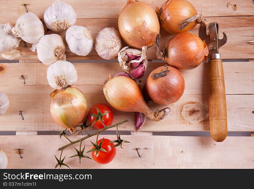 Onion, garlic and tomato on a wooden desk in sun shine