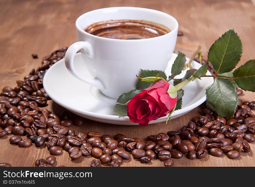 White cup of black coffee with coffee beans and red rose