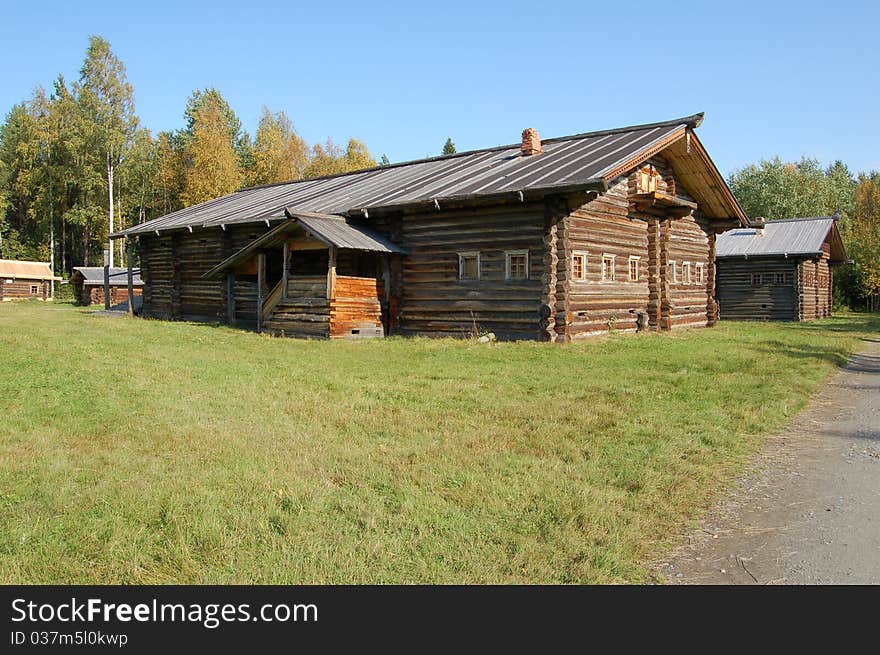 The wooden house in village and green vegetation, on a background is visible wood.