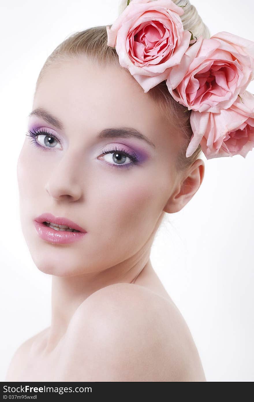 Portrait of young beautiful woman with roses in hair, on white background