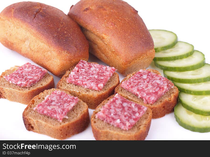 Little tasty sandwiches with sausage and homemade loafs of rye bread with cucumber isolated on white background. Little tasty sandwiches with sausage and homemade loafs of rye bread with cucumber isolated on white background