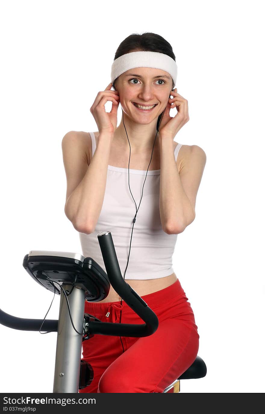 Happy young woman in red sport clothes on a training bicycle; isolated on white. Happy young woman in red sport clothes on a training bicycle; isolated on white