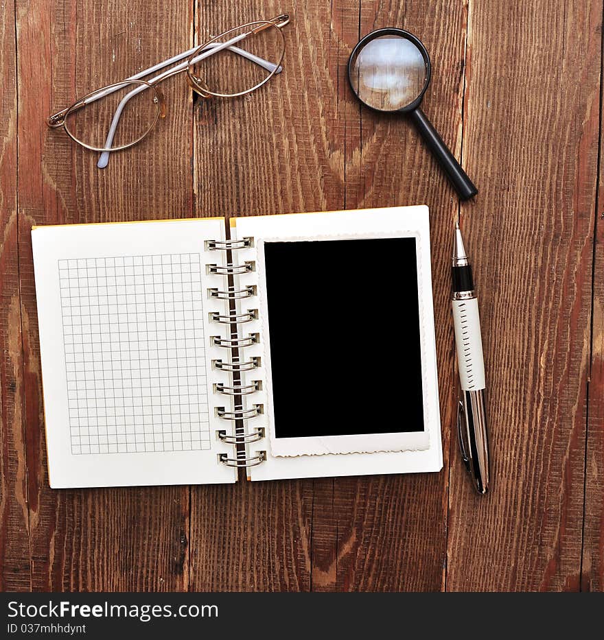 Note with old photo, pen, magnifying glass and eyeglasses on wood background. Note with old photo, pen, magnifying glass and eyeglasses on wood background