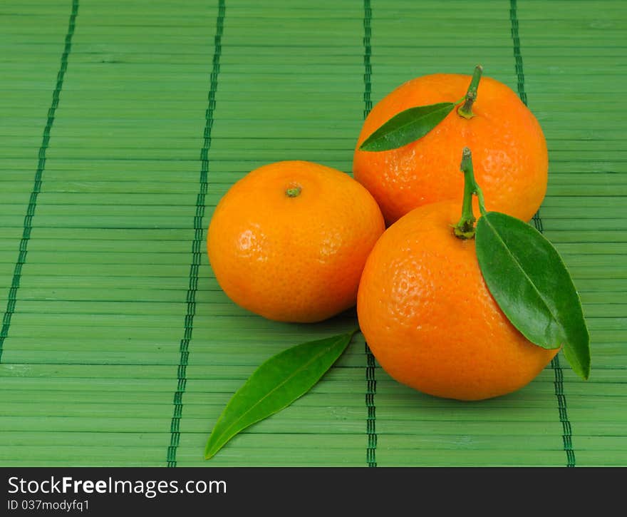 Several mandarins and leaves on green background. Several mandarins and leaves on green background