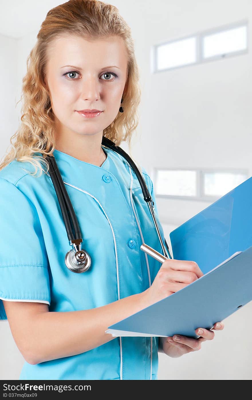 Beautiful young doctor with file folder and stethoscope in hospital