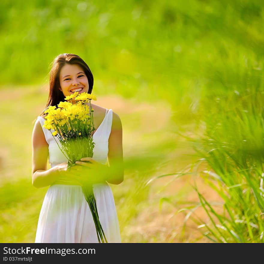 Adorable girl with flowers poses in a field during summer afternoon. Adorable girl with flowers poses in a field during summer afternoon.