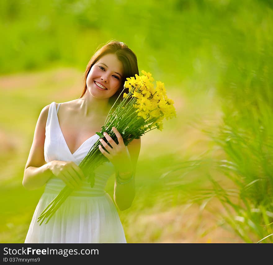 Adorable girl with flowers poses in a field during summer afternoon. Adorable girl with flowers poses in a field during summer afternoon.