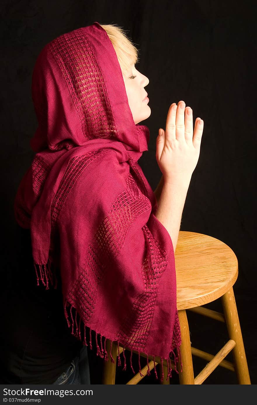 Woman wearing red scarf praying, black background. Woman wearing red scarf praying, black background