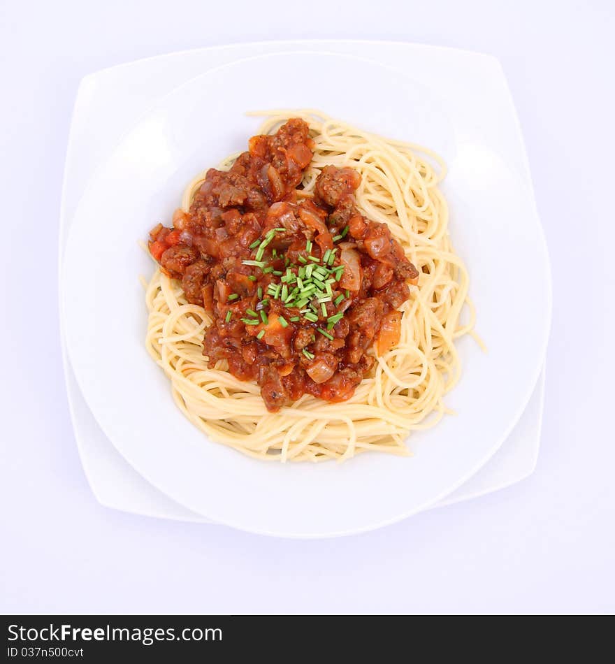 Spaghetti bolognese on a plate decorated with some chives