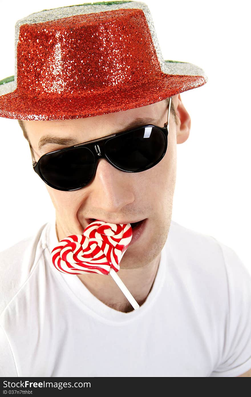 Young man in sun glasses with a candy in the shape of a heart on the white background