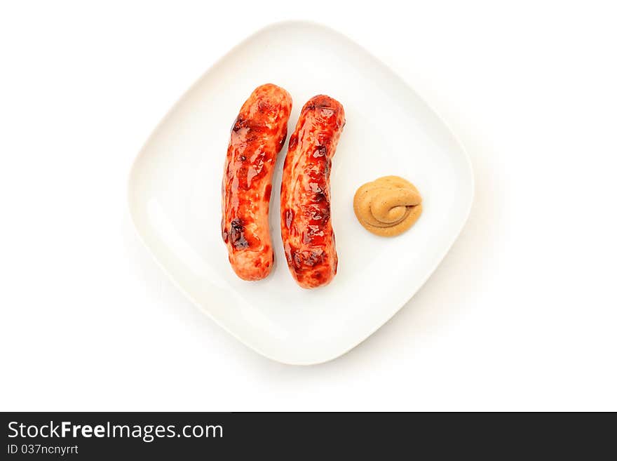 Appetizing grilled sausages with mustard on a plate.