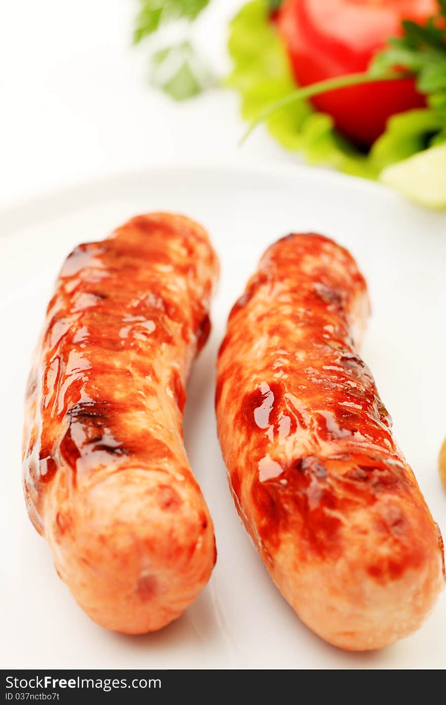 Appetizing grilled sausages with vegetables on a plate. Appetizing grilled sausages with vegetables on a plate.