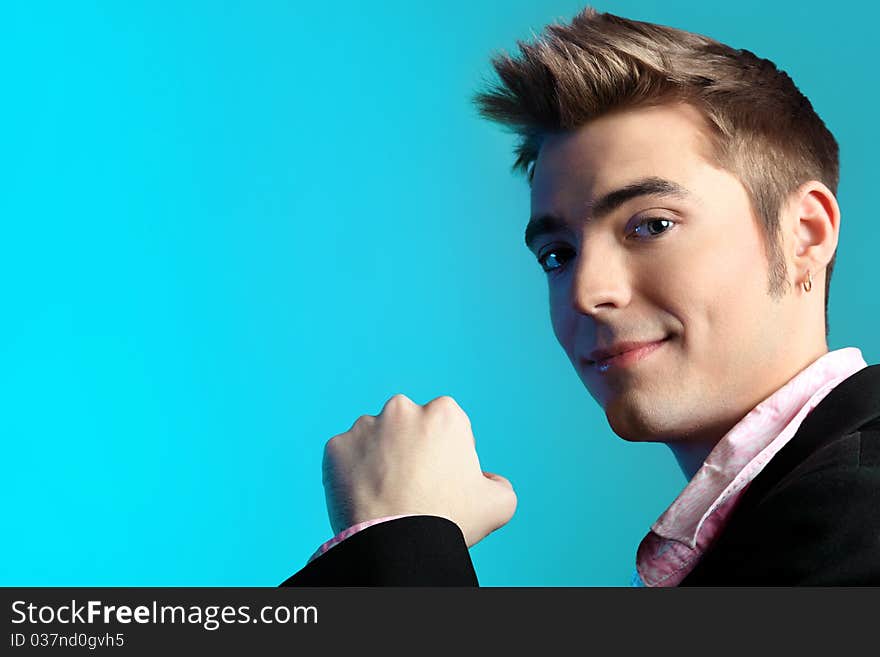 Young man dressed in rock'n'roll style, posing over blue background. Young man dressed in rock'n'roll style, posing over blue background.