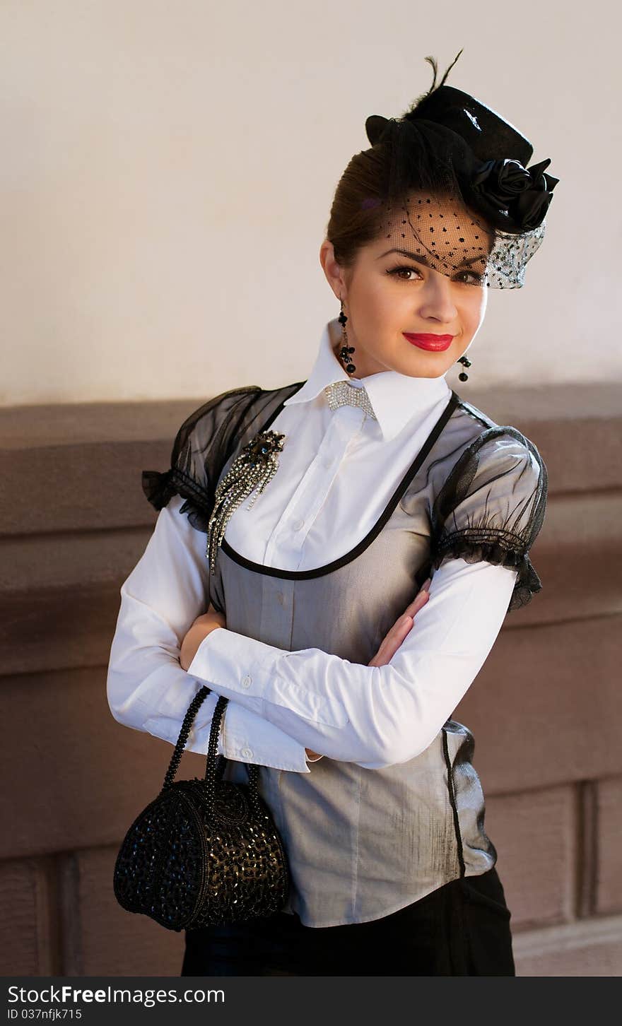 Portrait of a fresh and lovely woman wearing a hat with a veil and white blouse with a brooch on her breast holding a handbag. Portrait of a fresh and lovely woman wearing a hat with a veil and white blouse with a brooch on her breast holding a handbag