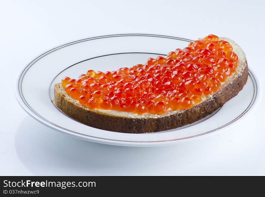 Red caviar sandwich with a brow bread on the plate over the light background