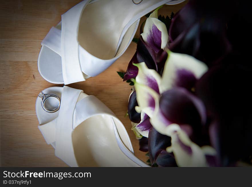 A bride's high heel shoes and wedding rings, bands and bouquet. A bride's high heel shoes and wedding rings, bands and bouquet