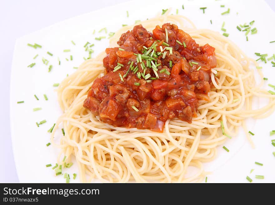 Spaghetti bolognese on a plate decorated with some chives