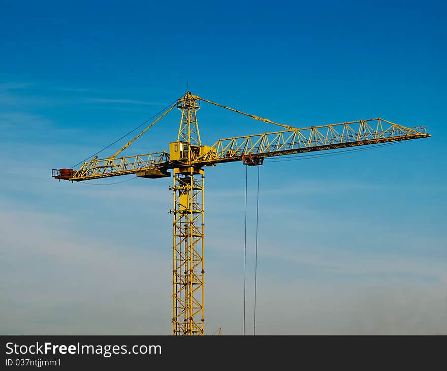 High building crane against the blue sky background. High building crane against the blue sky background