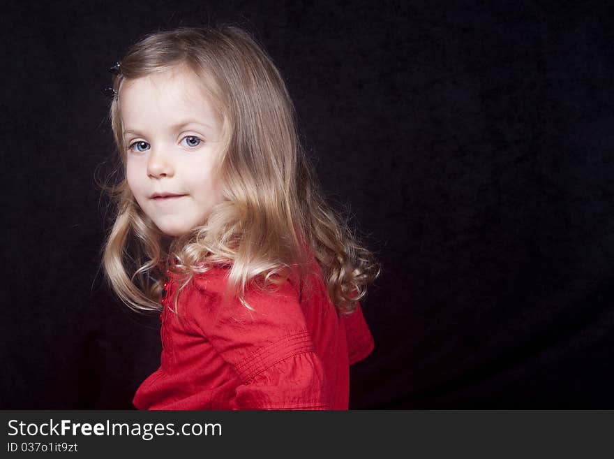 A little girl in red dress looking at camera with small smile. A little girl in red dress looking at camera with small smile