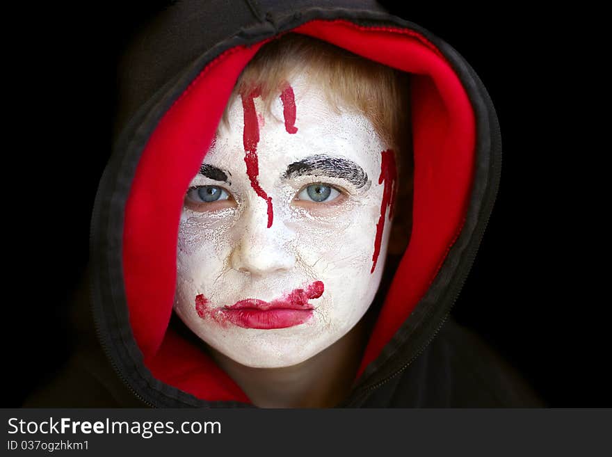 Boy in red hood with painted face on halloween.