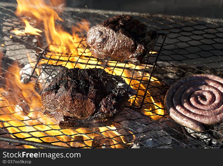 Traditional South African sausage called boerewors or just simply wors being grilled on a traditional braai along with sirloin steak. Traditional South African sausage called boerewors or just simply wors being grilled on a traditional braai along with sirloin steak