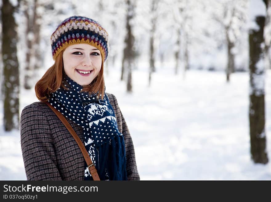 Beautiful young red-haired woman in winter park. Outdoor shot.