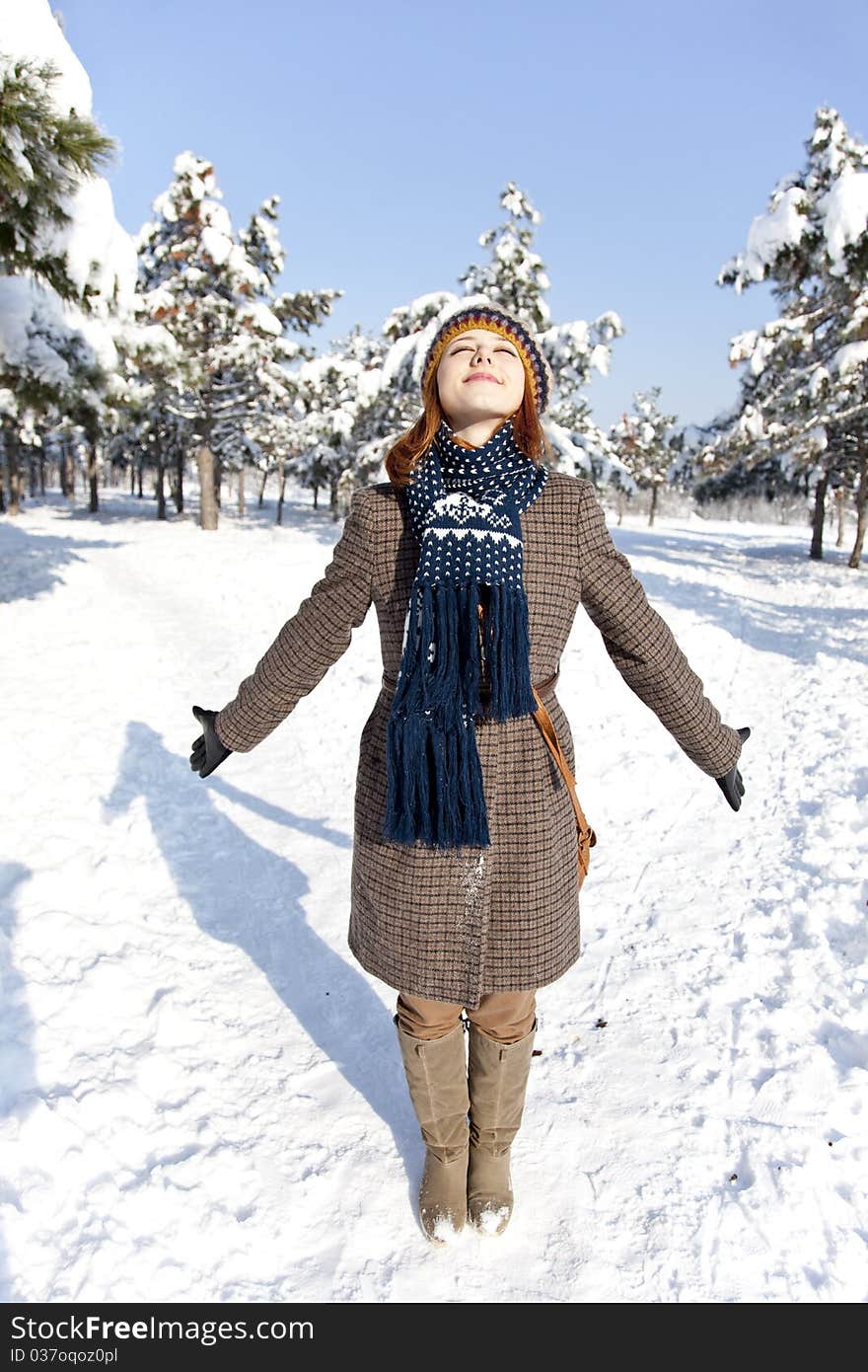 Beautiful young red-haired woman in winter park. Outdoor shot.