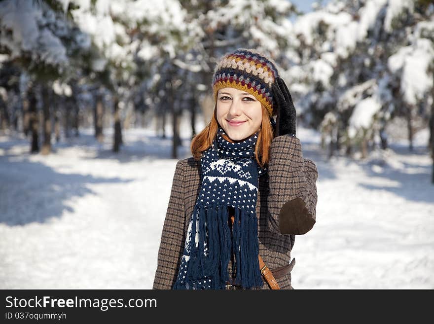 Beautiful young red-haired woman in winter park. Outdoor shot.