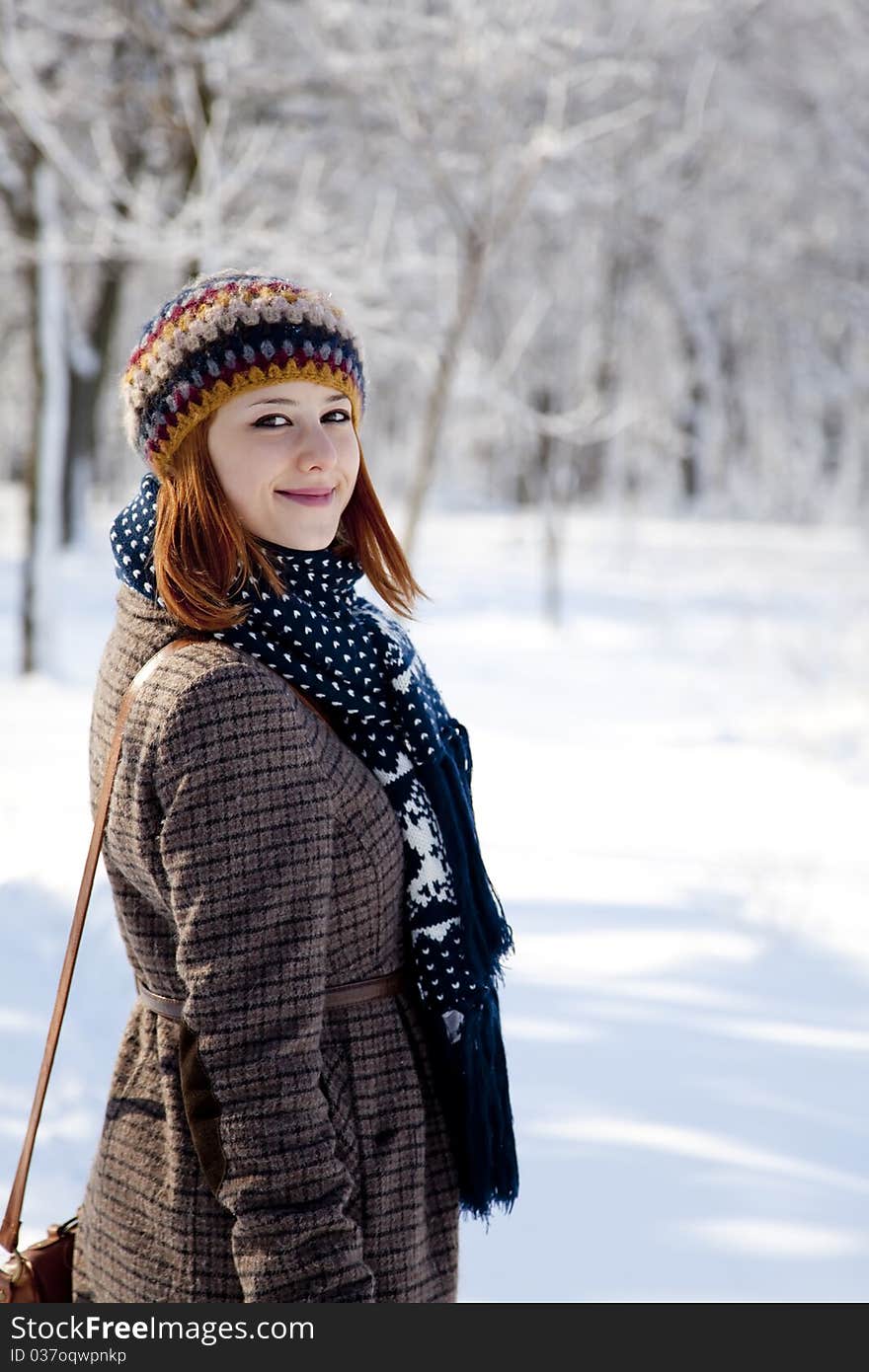 Beautiful young red-haired woman in winter park. Outdoor shot.