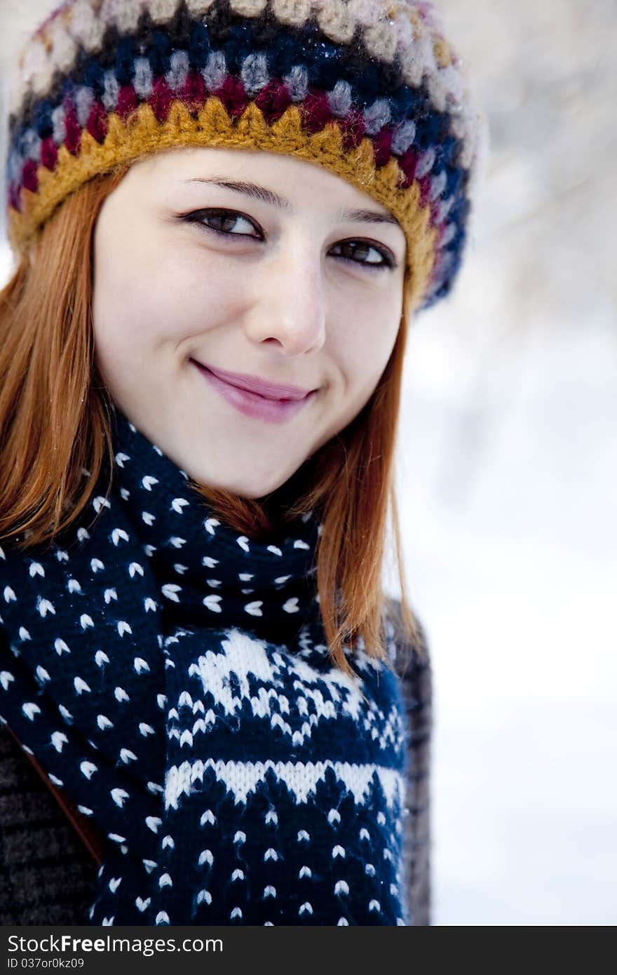 Beautiful young red-haired woman in winter park. Outdoor shot.