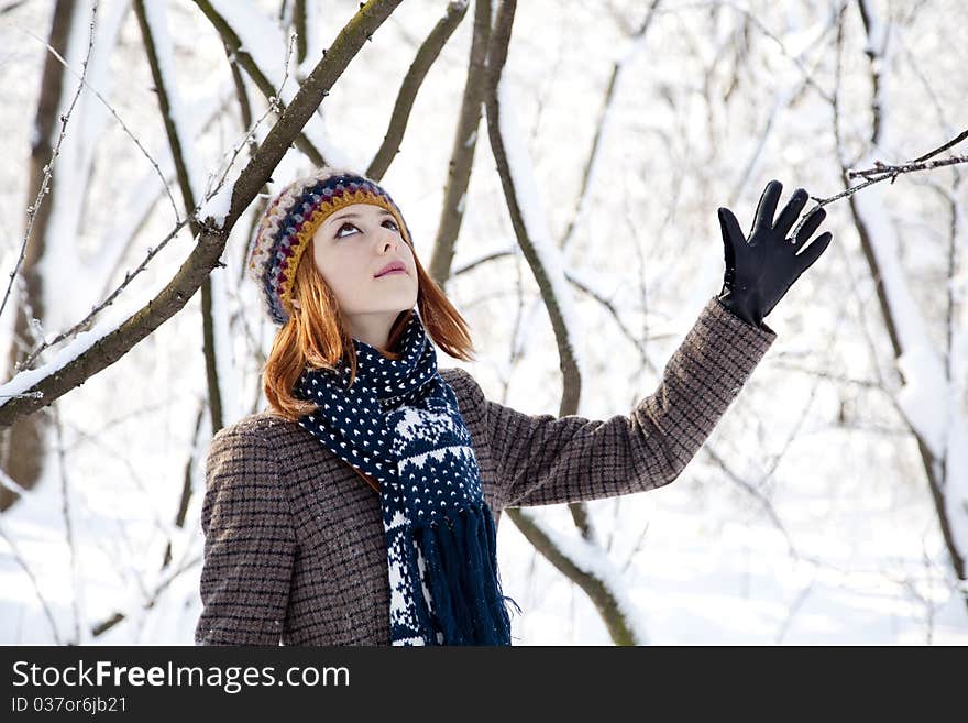 Beautiful young red-haired woman in winter park. Outdoor shot.