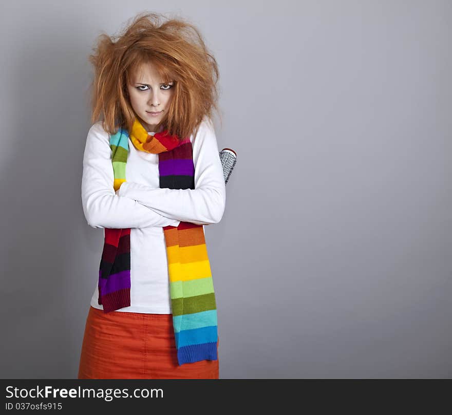 Sad red-haired girl with comb. Studio shot.